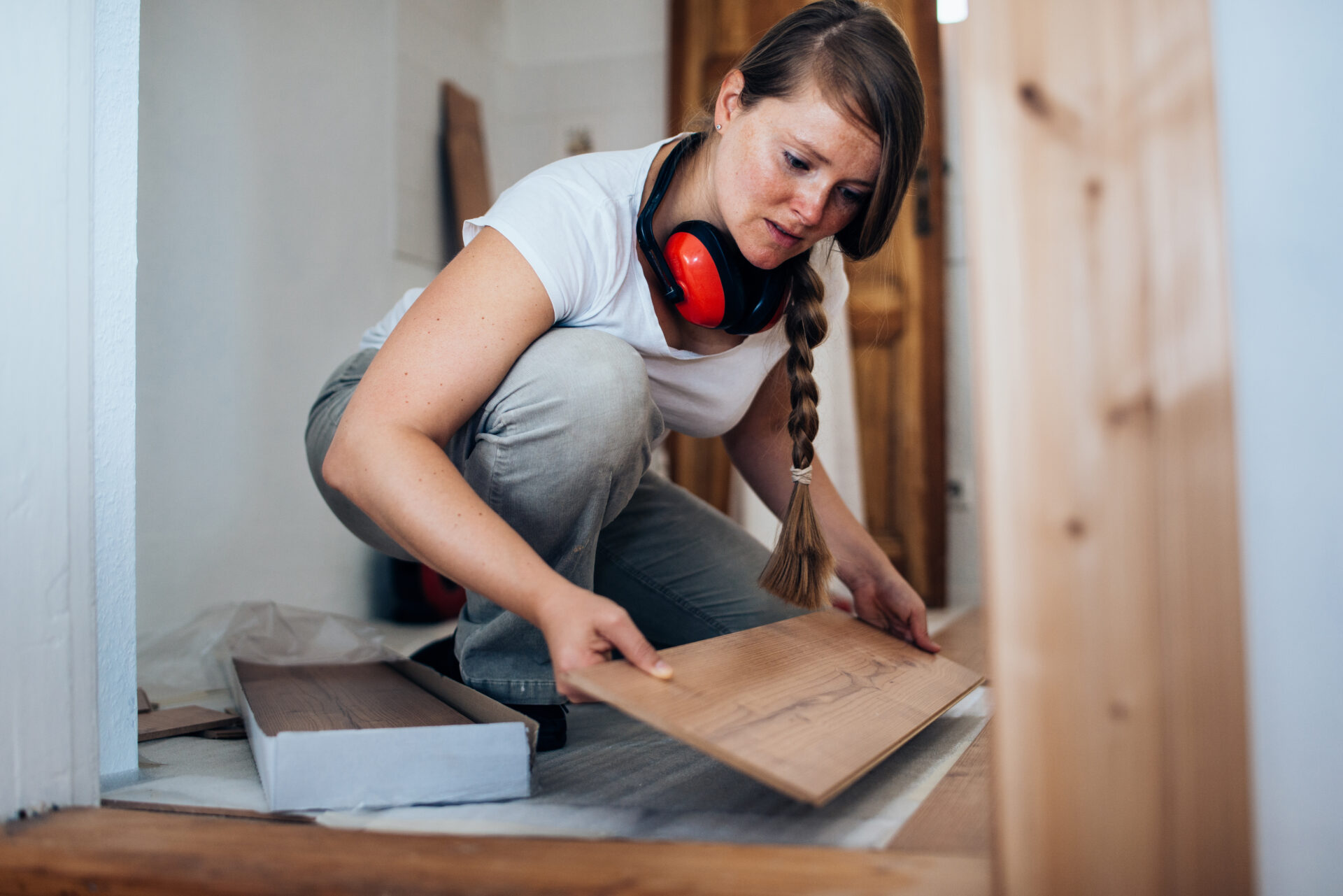 Woman installing laminate flooring.