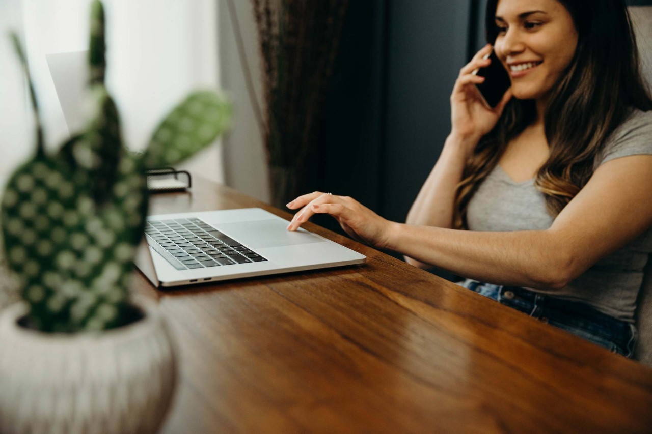 Woman sitting at a table with a laptop and phone